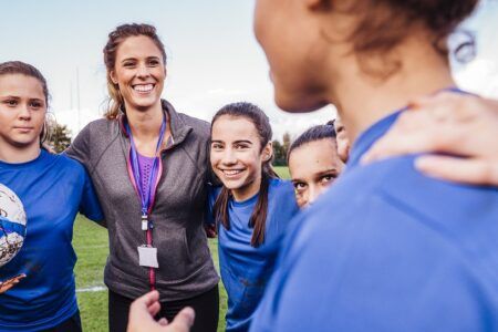 Female football coach talking to team on field