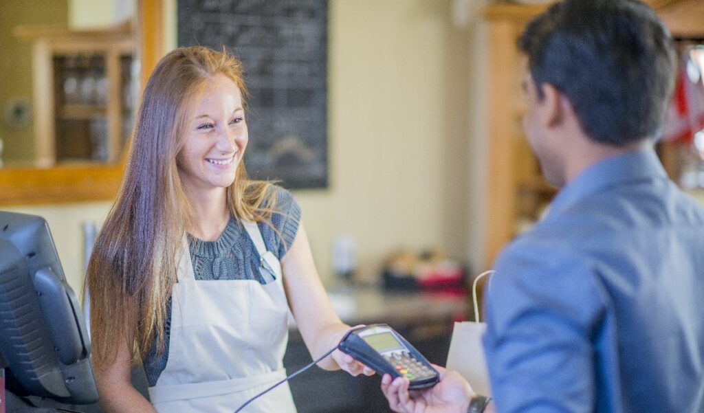 Female student serving someone in a shop