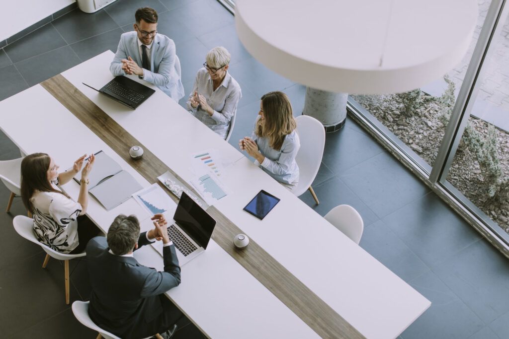 four people in a business meeting sat at a desk