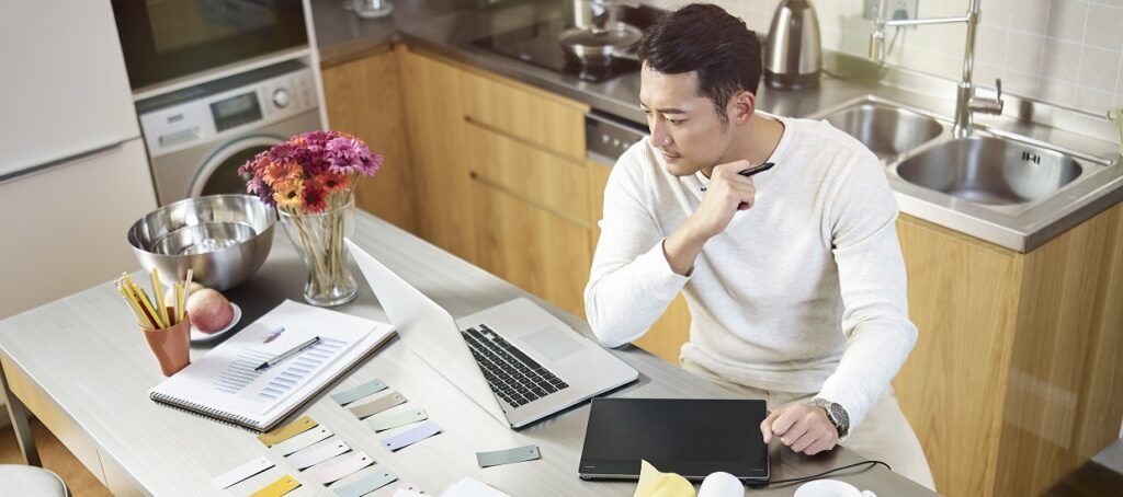 Man sitting at kitchen table working from home on laptop