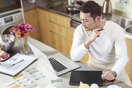 Man sitting at kitchen table working from home on laptop