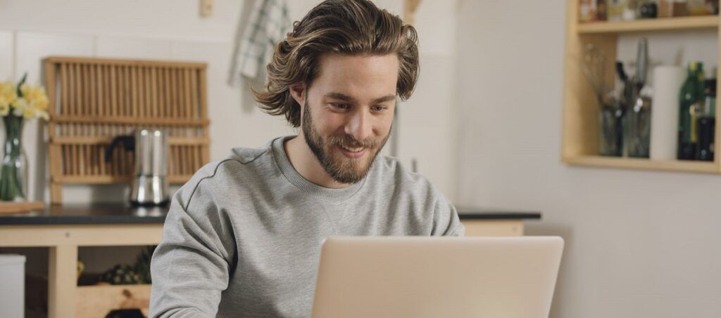 Man working at table on laptop smiling 2