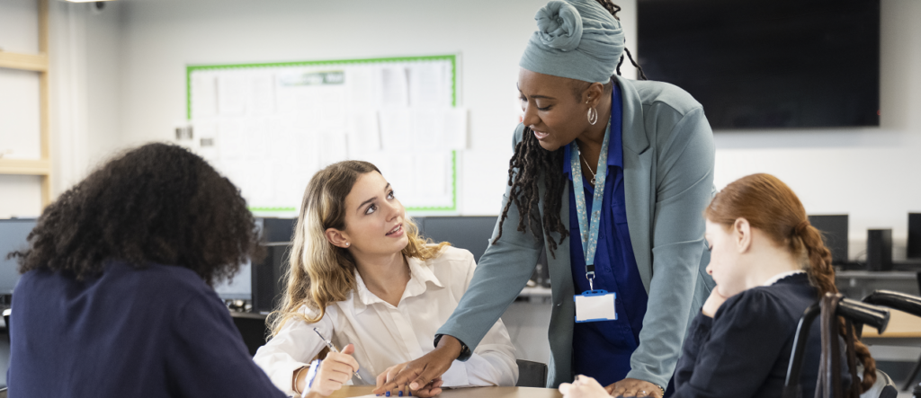 Teacher helping pupils with work in classroom