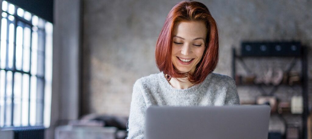 Woman working on laptop at home smiling