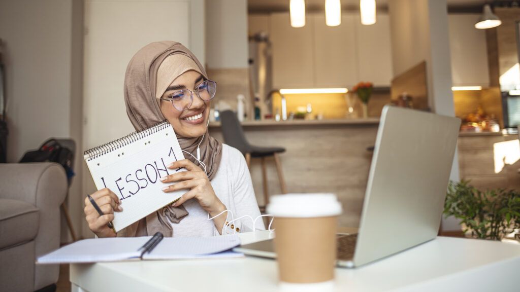 Women holding a notebook in front of her laptop 1