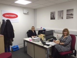 two unitemps staff sitting at desks working on computers