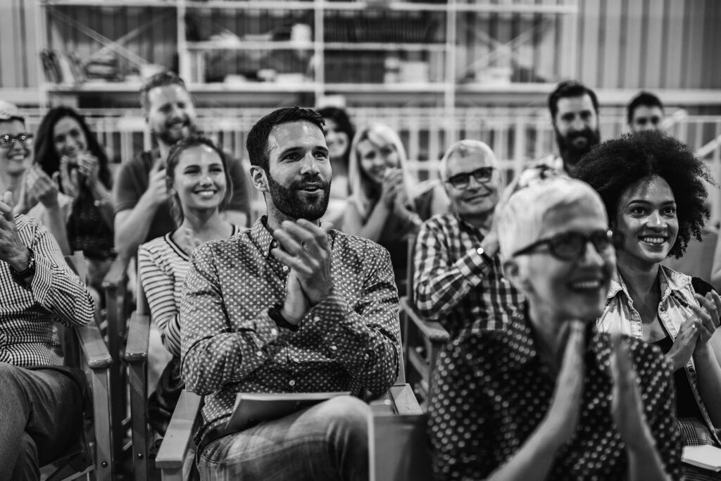 gathering of people sitting down smiling and clapping