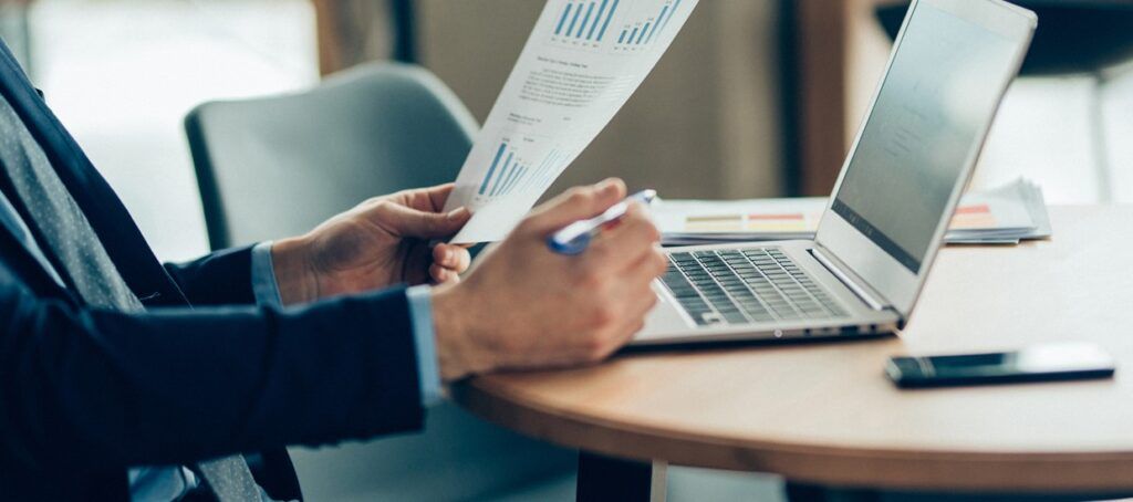 man at desk with laptop and documents