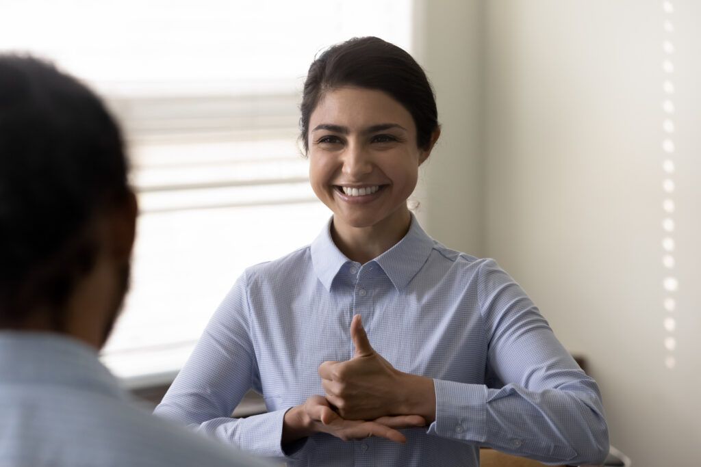 Smiling young woman who is deaf using sign language